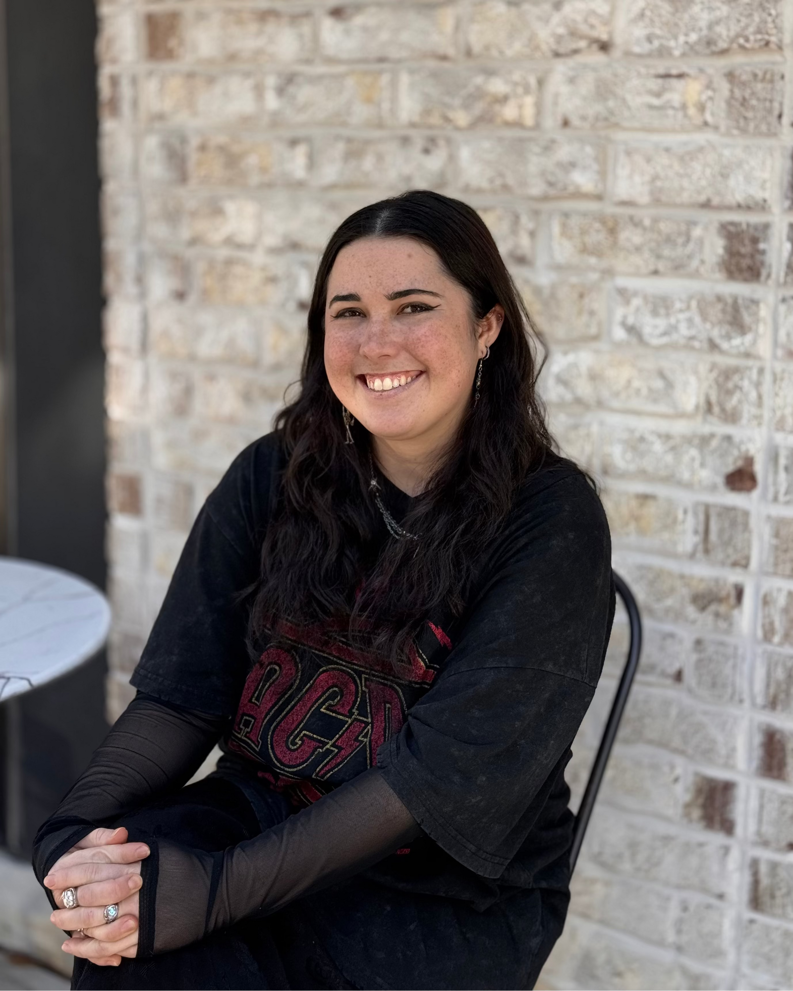 barista sitting against a brick wall, wearing a black shirt