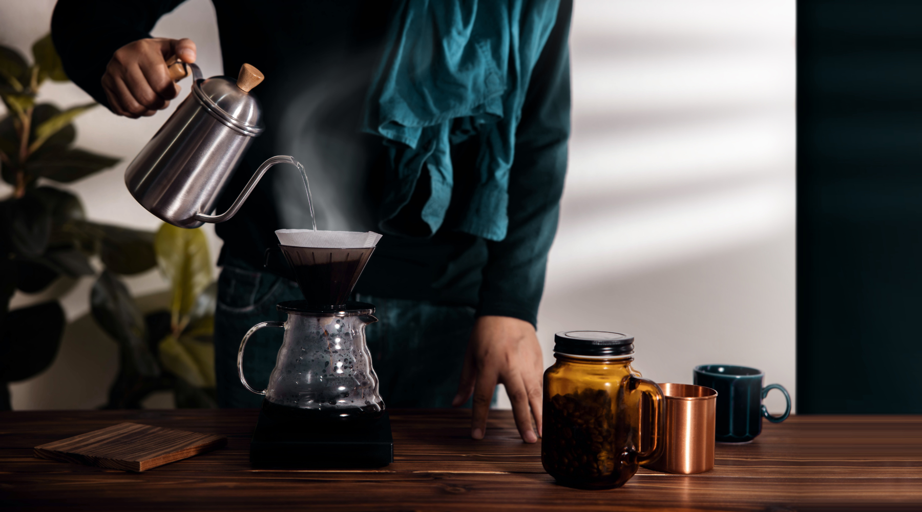 image of person brewing coffee at home using a kalita wave pour over stand and silver kettle
