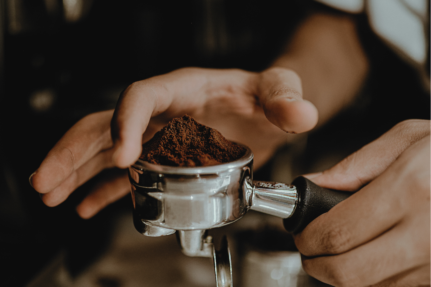 Person holding a portafilter with ground coffee