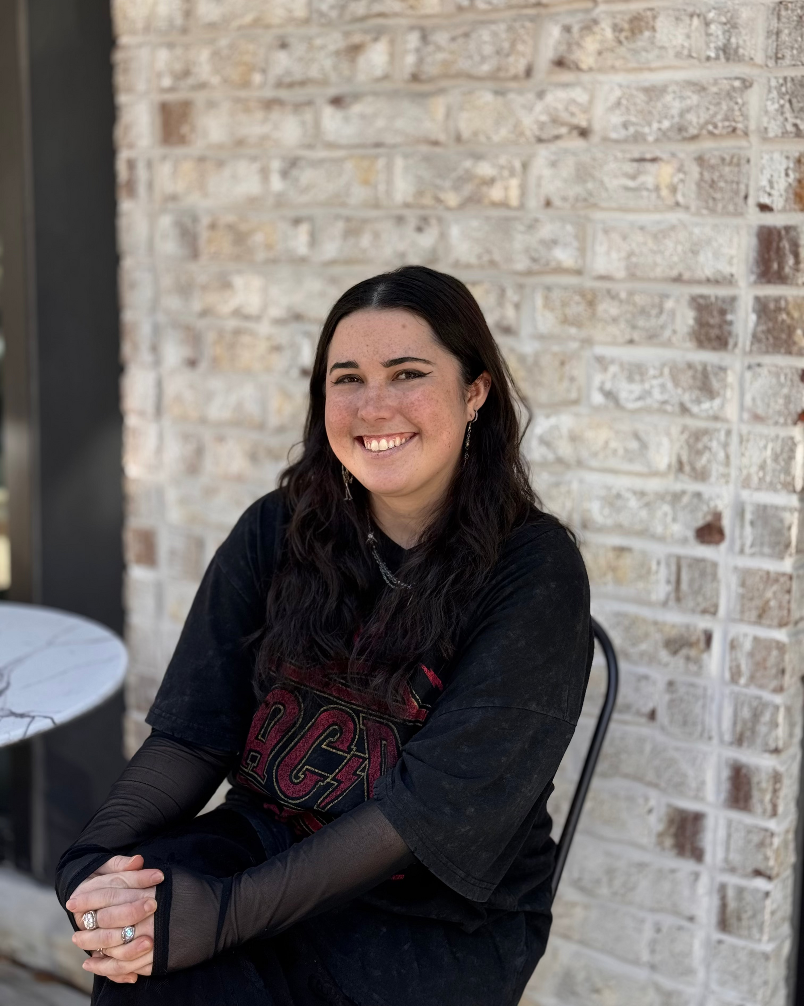 barista sitting against a brick wall, wearing a black shirt