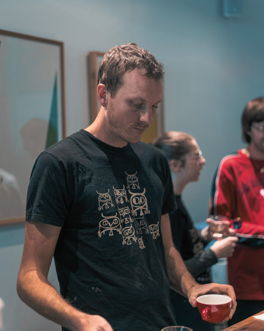 coffee professional tasting coffee at cupping table wearing second state coffee tshirt merch